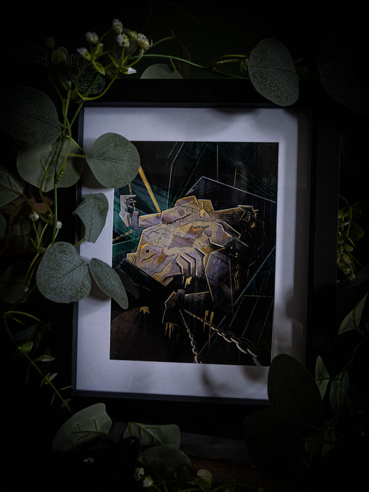 Overhead angled view of The Creature Awakens art print in black frame, dark atmospheric styling with trailing eucalyptus