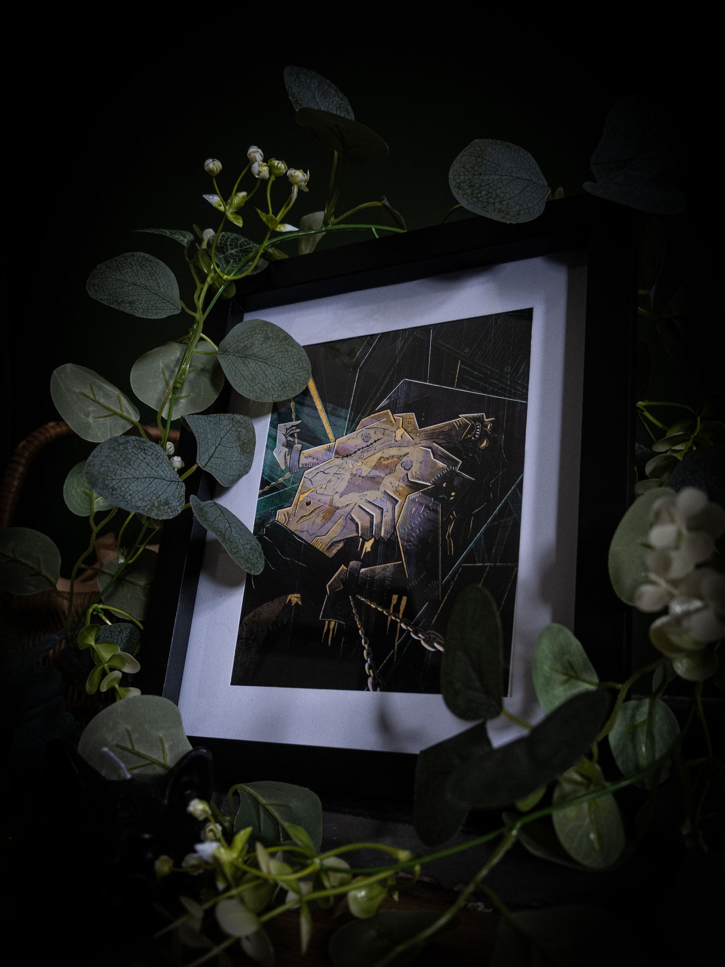 Frankenstein illustrated book art print in black frame, moody dark background with botanical props and candlelight atmosphere