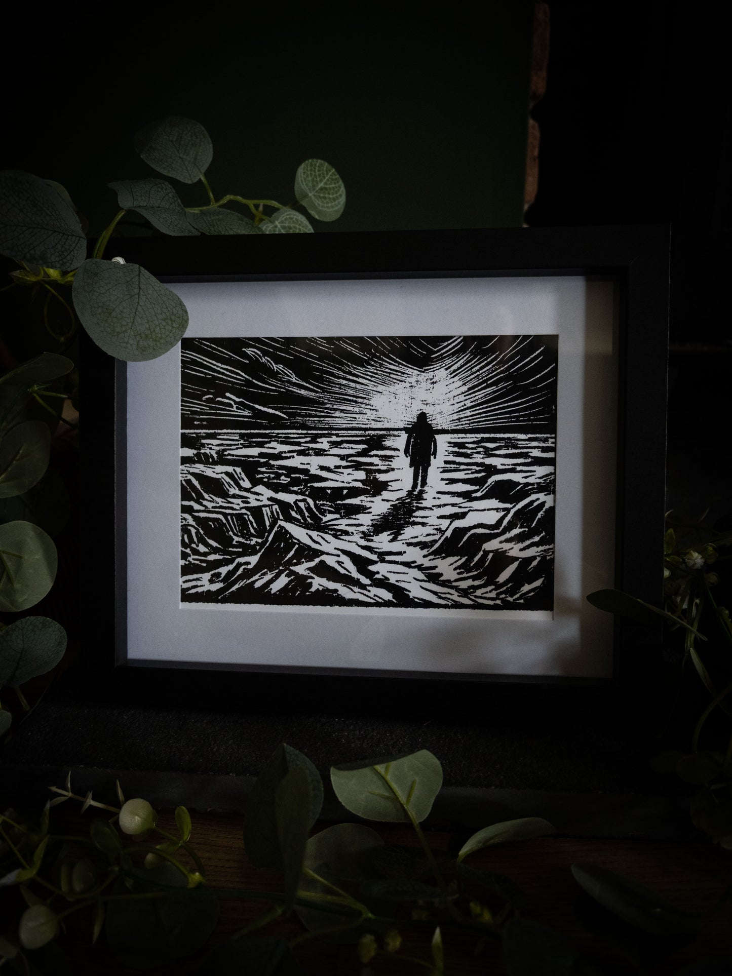 The Ice Plain giclée print displayed with eucalyptus foliage, high-contrast gothic illustration by Sophie Atkinson