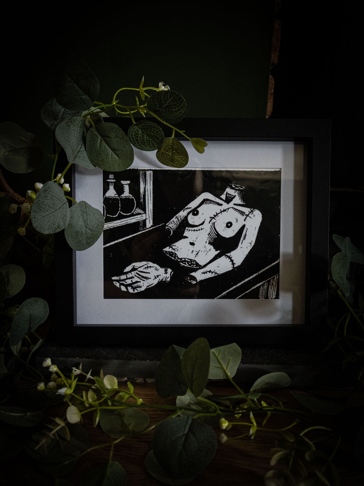The Workshop art print angled view — creature laid out in Victor's laboratory, bold black and white gothic illustration