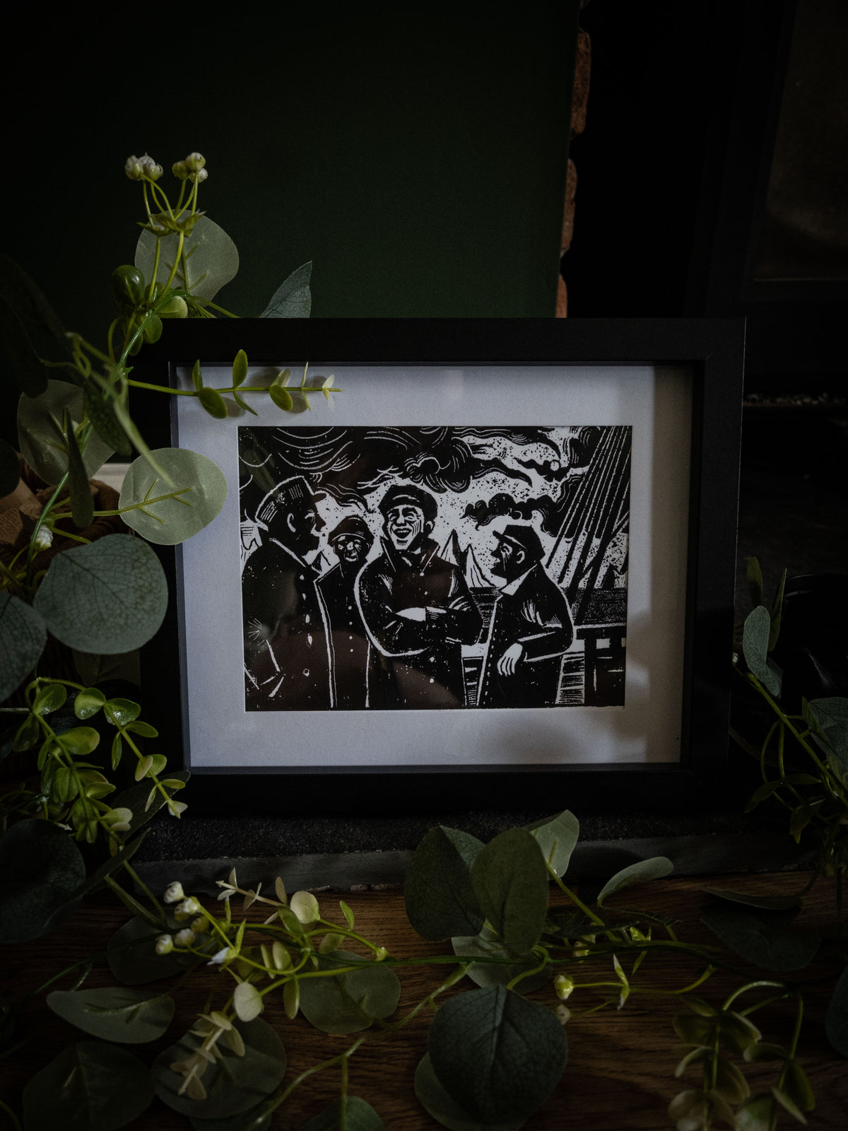 The Voyage giclée print in black frame with winter foliage — sailors laughing on deck, gothic horror illustration
