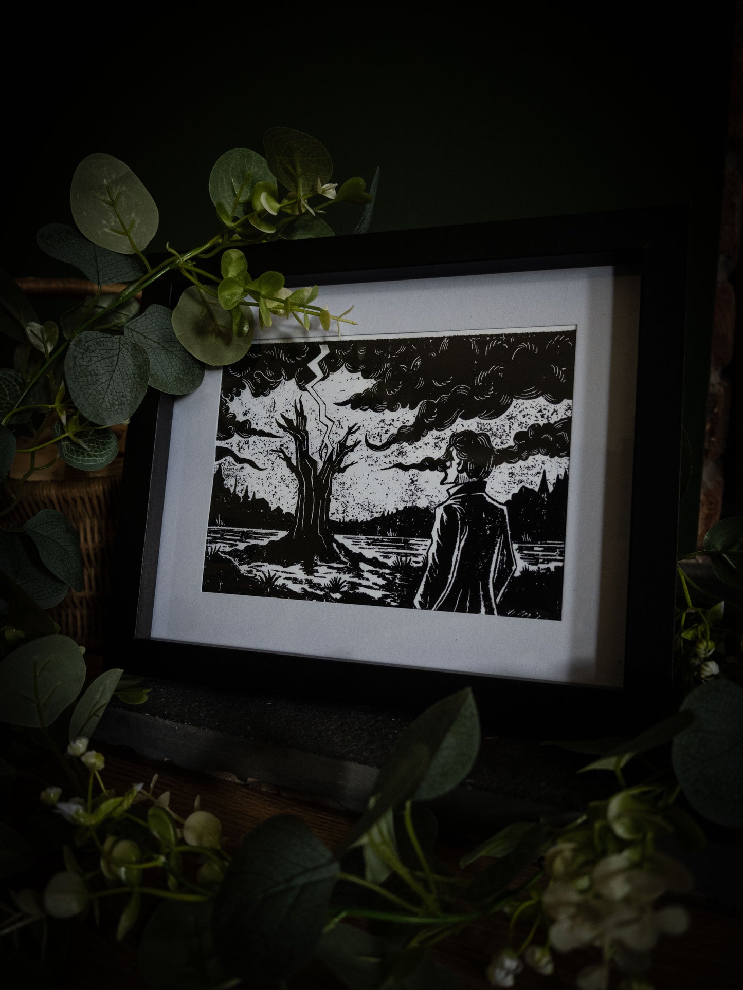 The Lightning Tree giclée print displayed with eucalyptus foliage, high-contrast gothic illustration by Sophie Atkinson