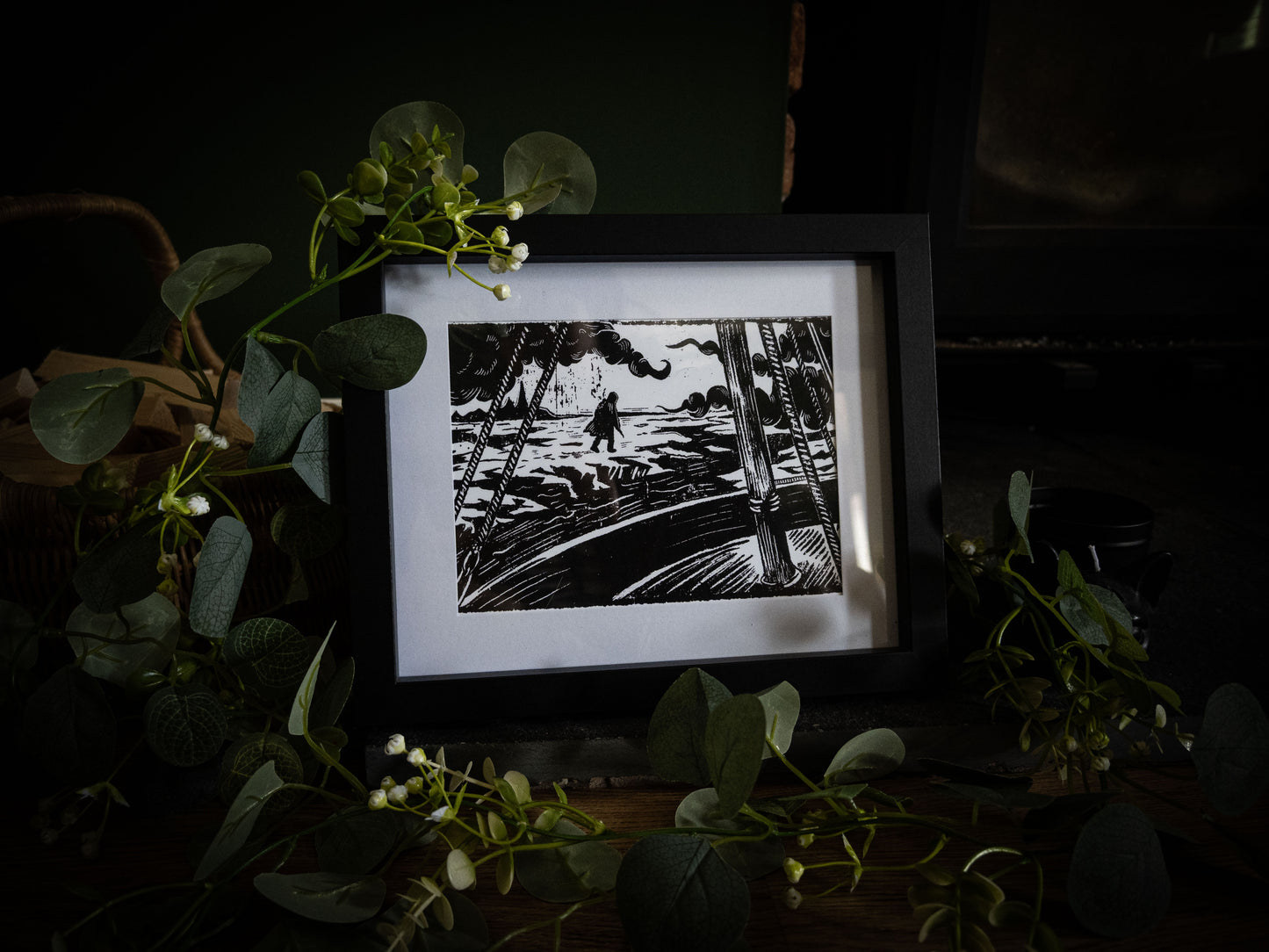 The Figure on the Ice art print in black frame with eucalyptus — bold gothic illustration of the creature spotted from Walton's ship, by Sophie Atkinson