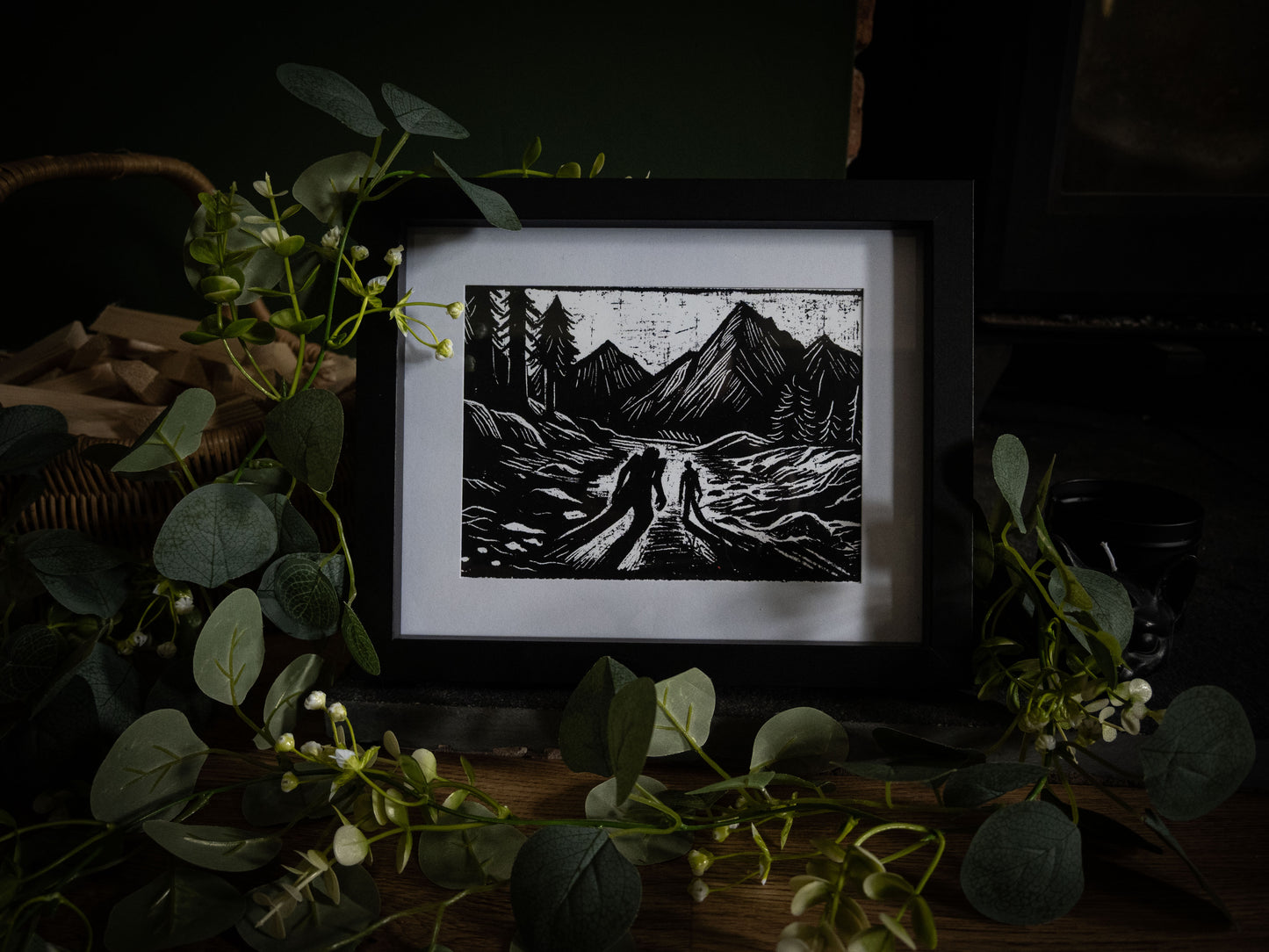 The Alpine Pass giclée print angled view — two figures on mountain path with jagged peaks, high-contrast gothic illustration by Sophie Atkinson