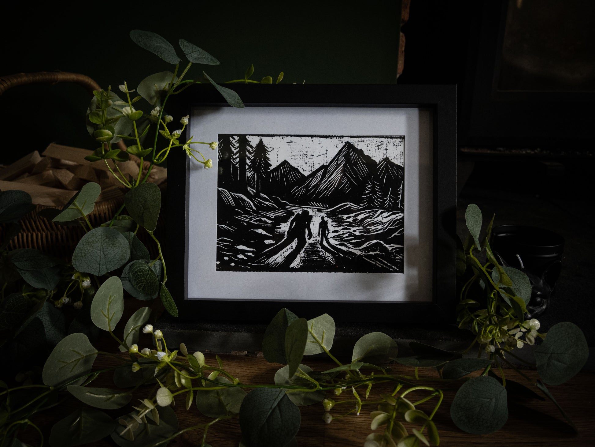 The Alpine Pass giclée print angled view — two figures on mountain path with jagged peaks, high-contrast gothic illustration by Sophie Atkinson