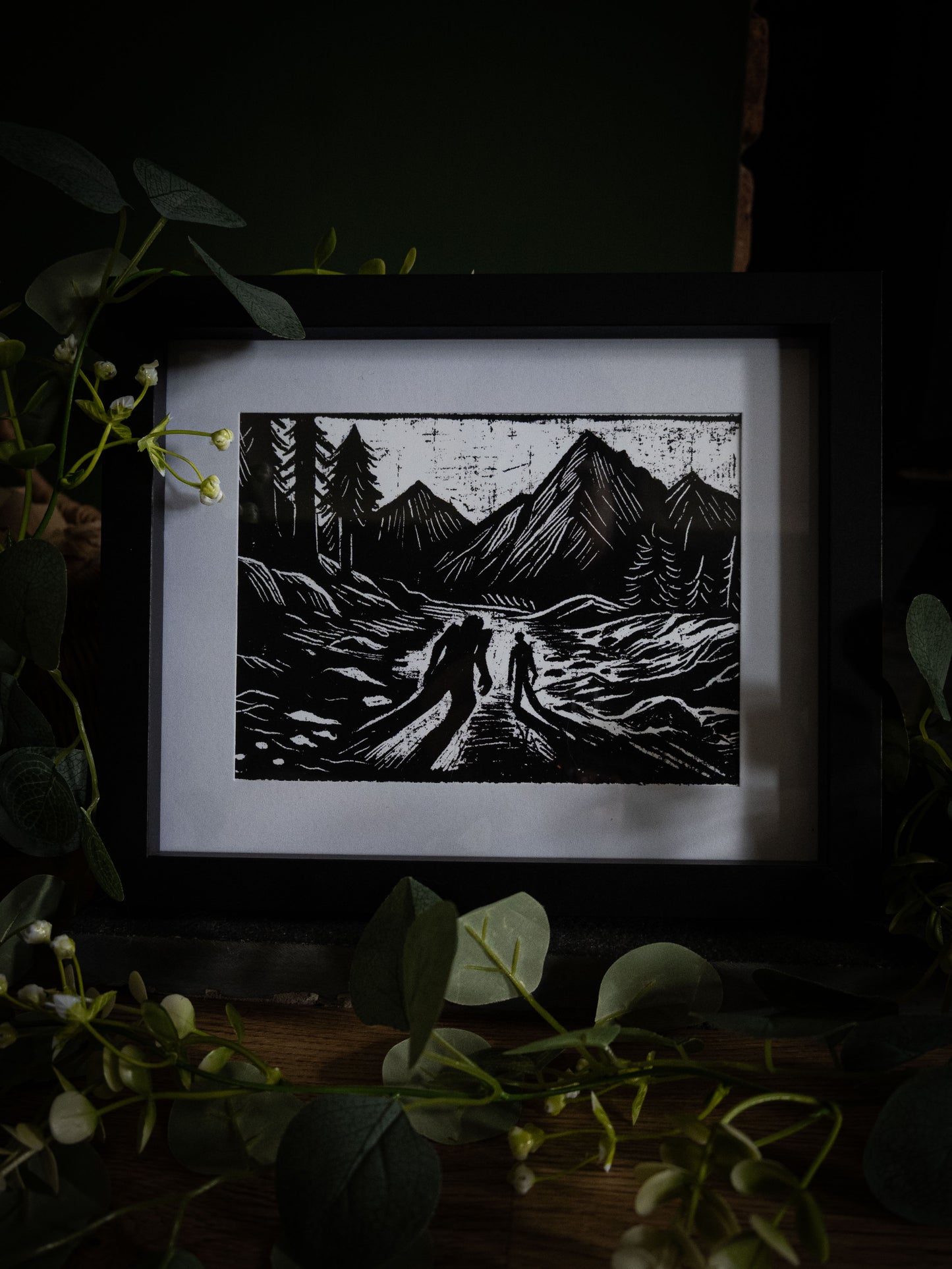 The Alpine Pass art print wide shot with eucalyptus — creator and creature on mountain path, bold black and white gothic illustration