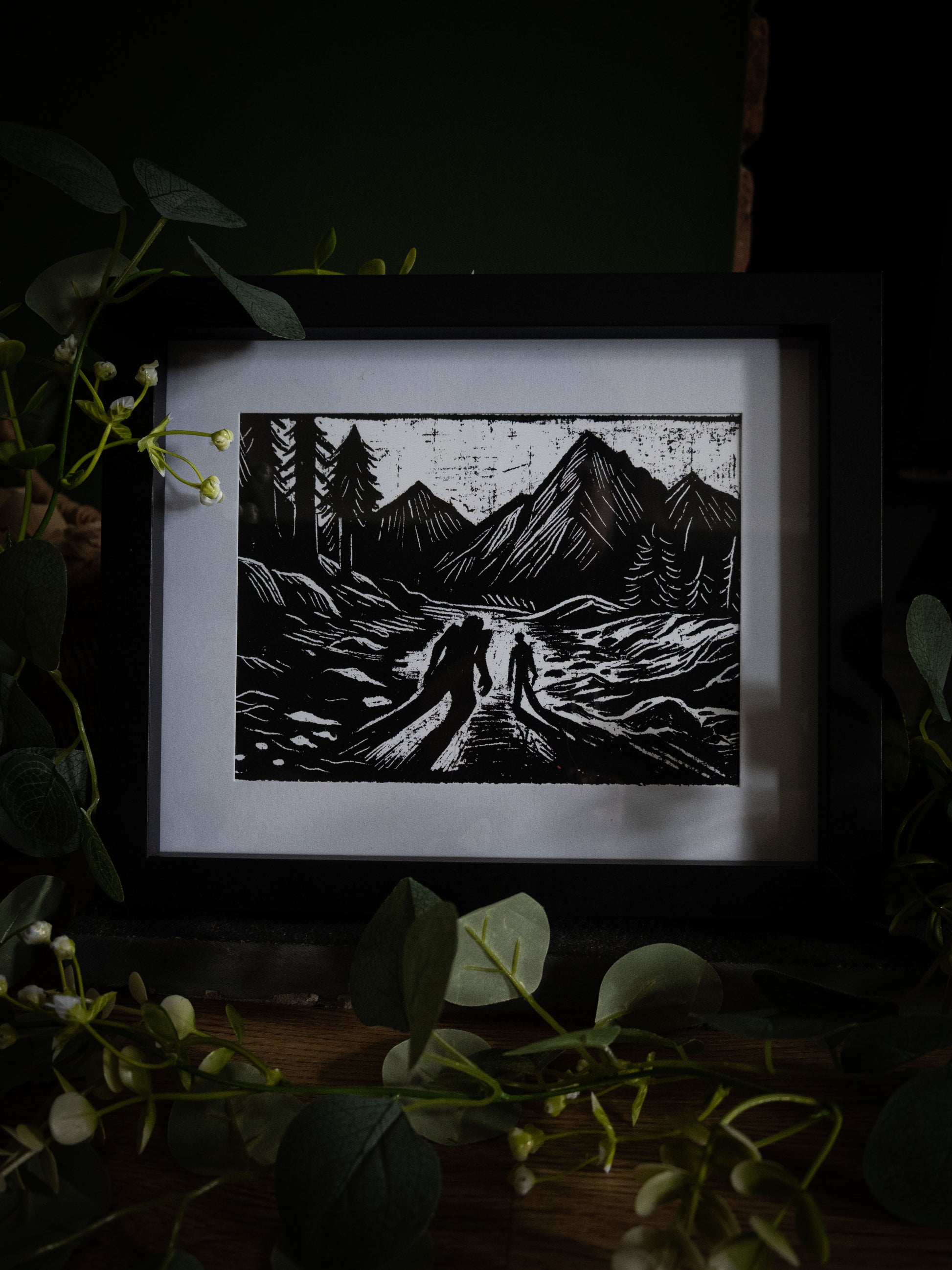The Alpine Pass art print wide shot with eucalyptus — creator and creature on mountain path, bold black and white gothic illustration