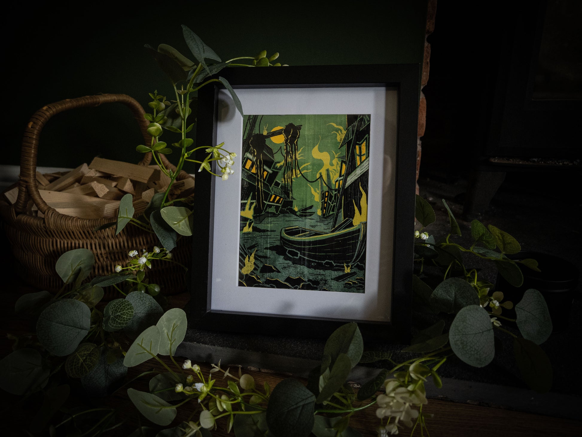 Something Wrong in Innsmouth gothic print – wide shot of framed Innsmouth harbour illustration with eucalyptus and white flowers on dark wooden surface