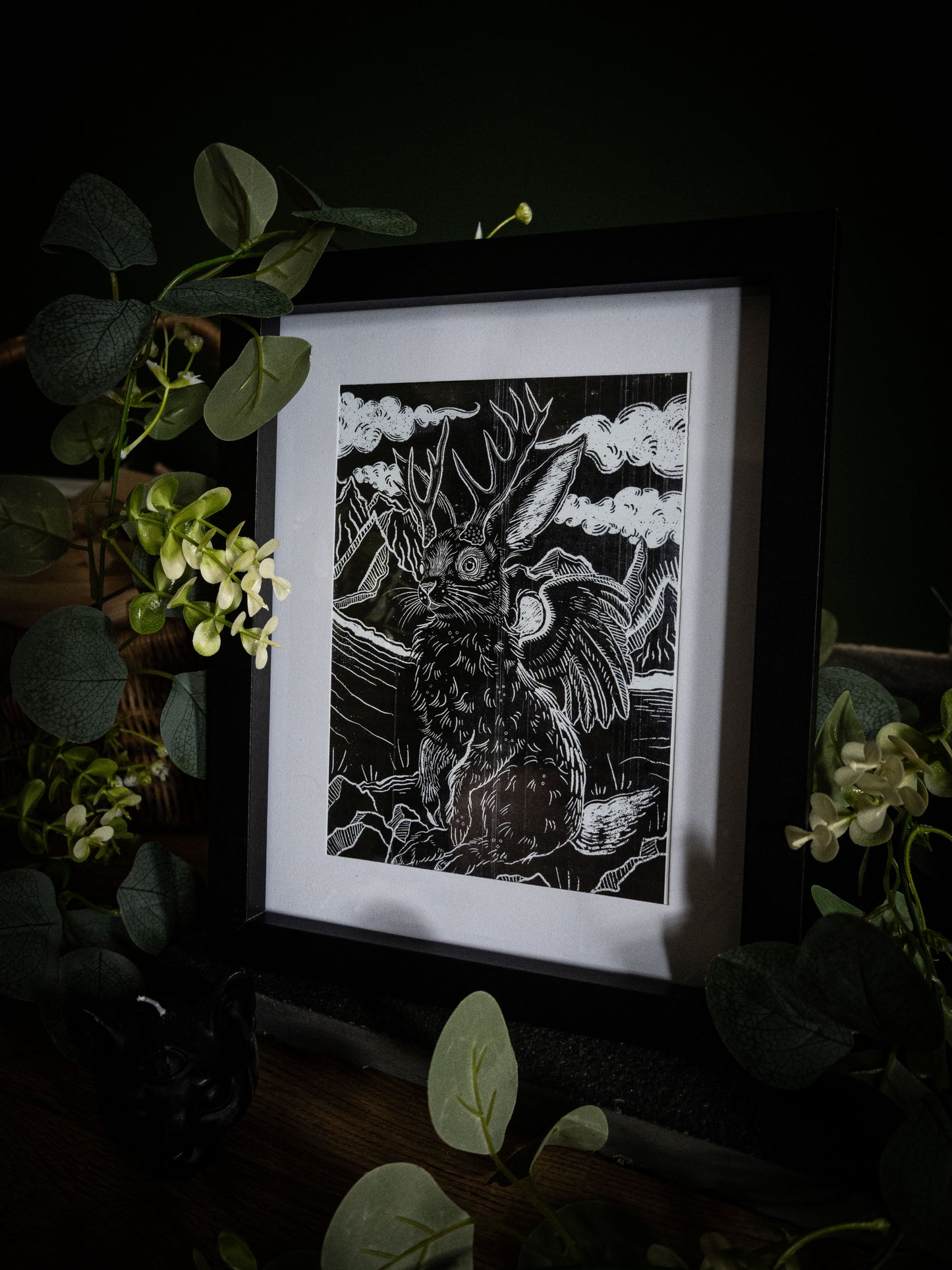 Sophie Atkinson Jackalope art print in black frame, dark atmospheric styling with botanical foliage