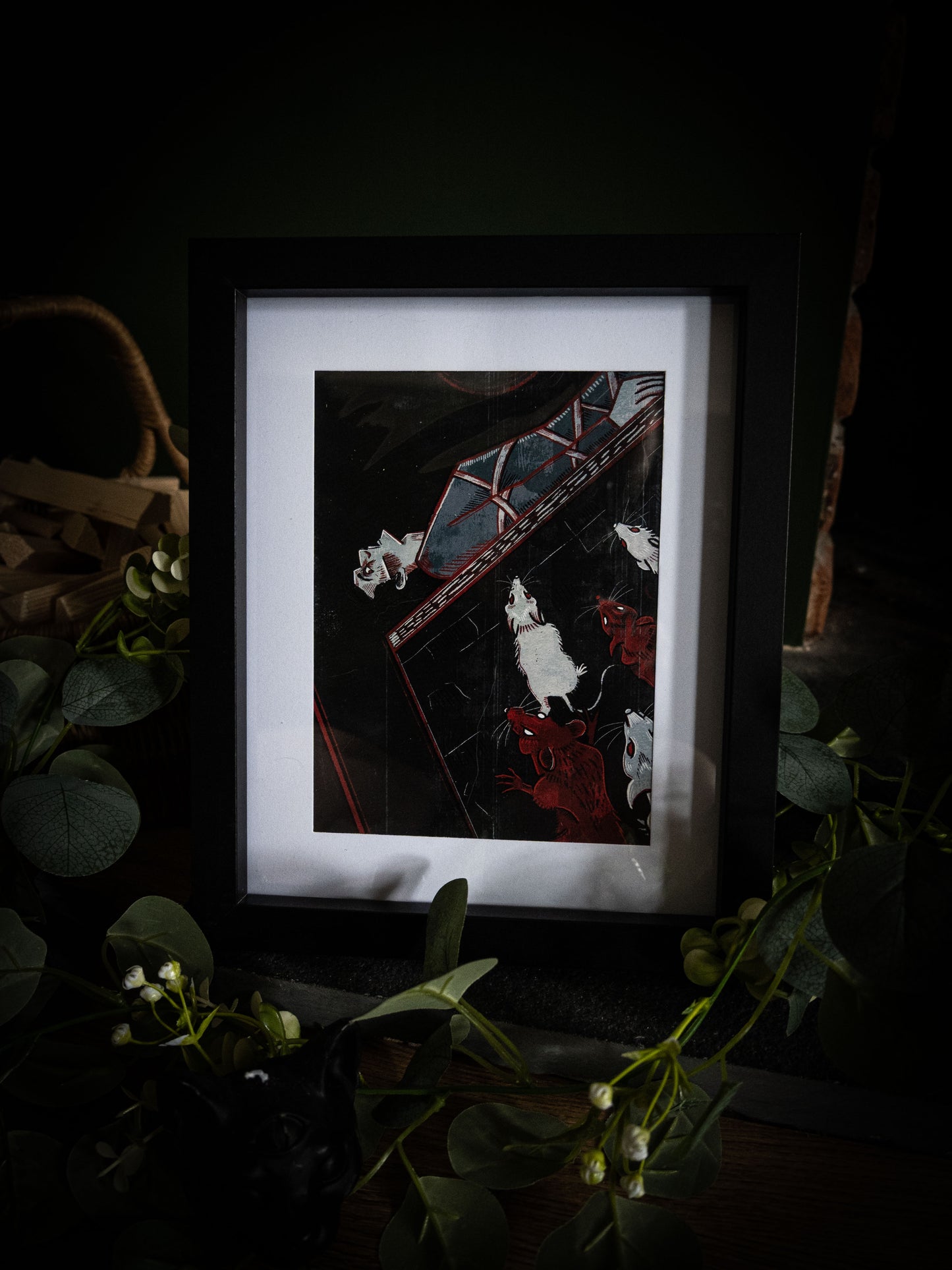 Full view of The Pit and the Pendulum gothic art print in black frame, deep black and crimson illustration with trailing eucalyptus and white blooms