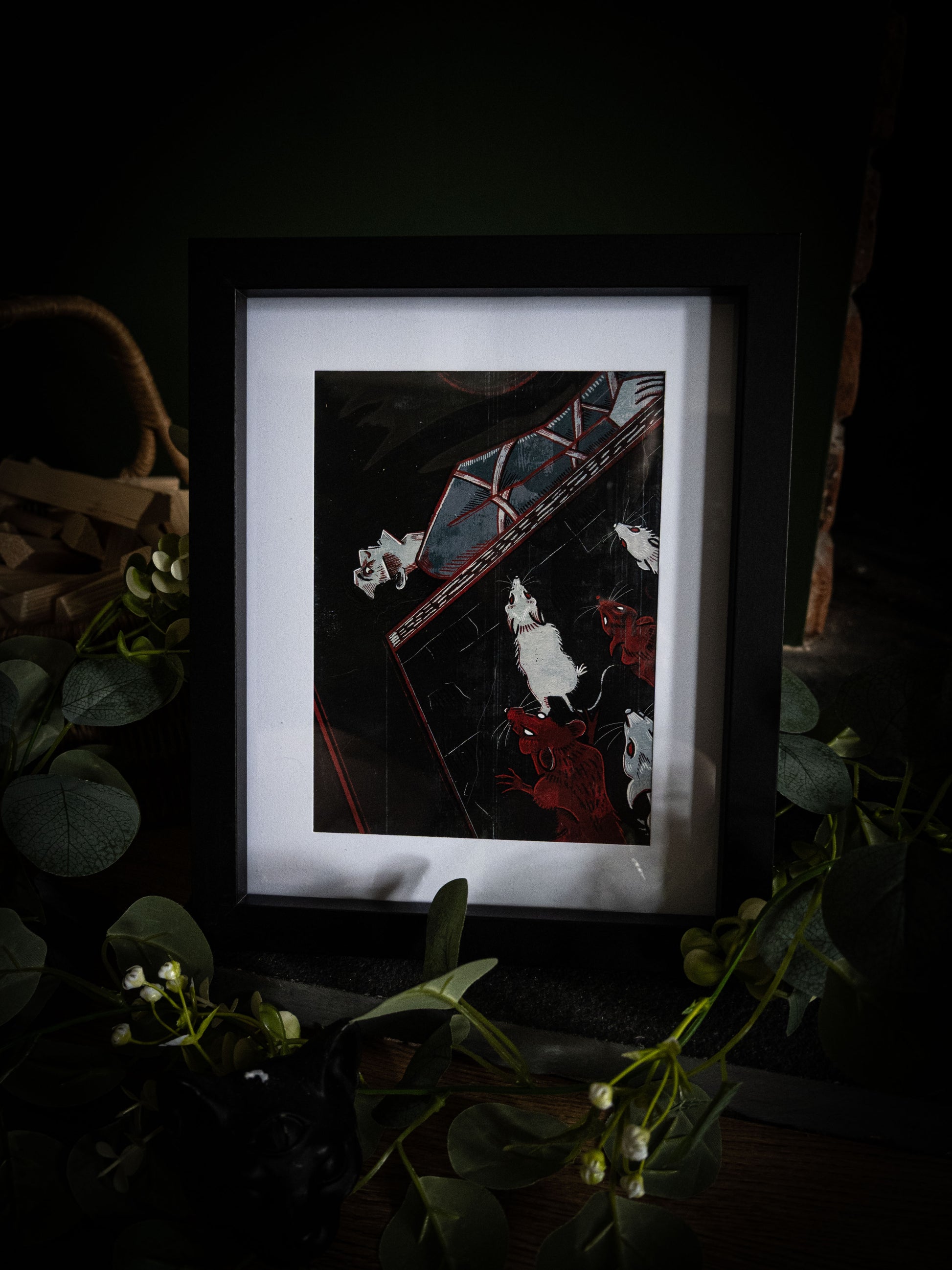 Full view of The Pit and the Pendulum gothic art print in black frame, deep black and crimson illustration with trailing eucalyptus and white blooms