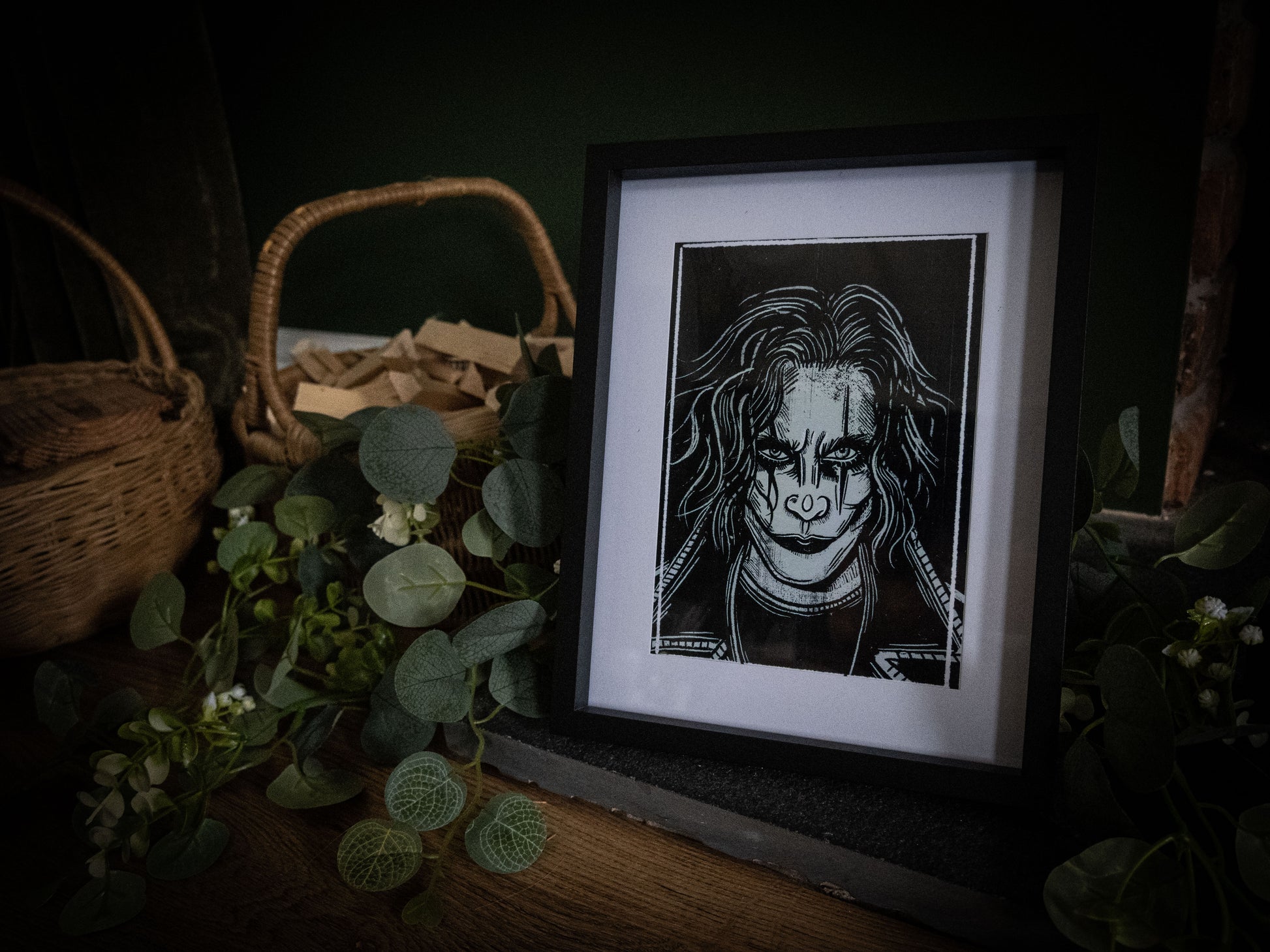 The Crow gothic print framed in black on dark background with botanicals