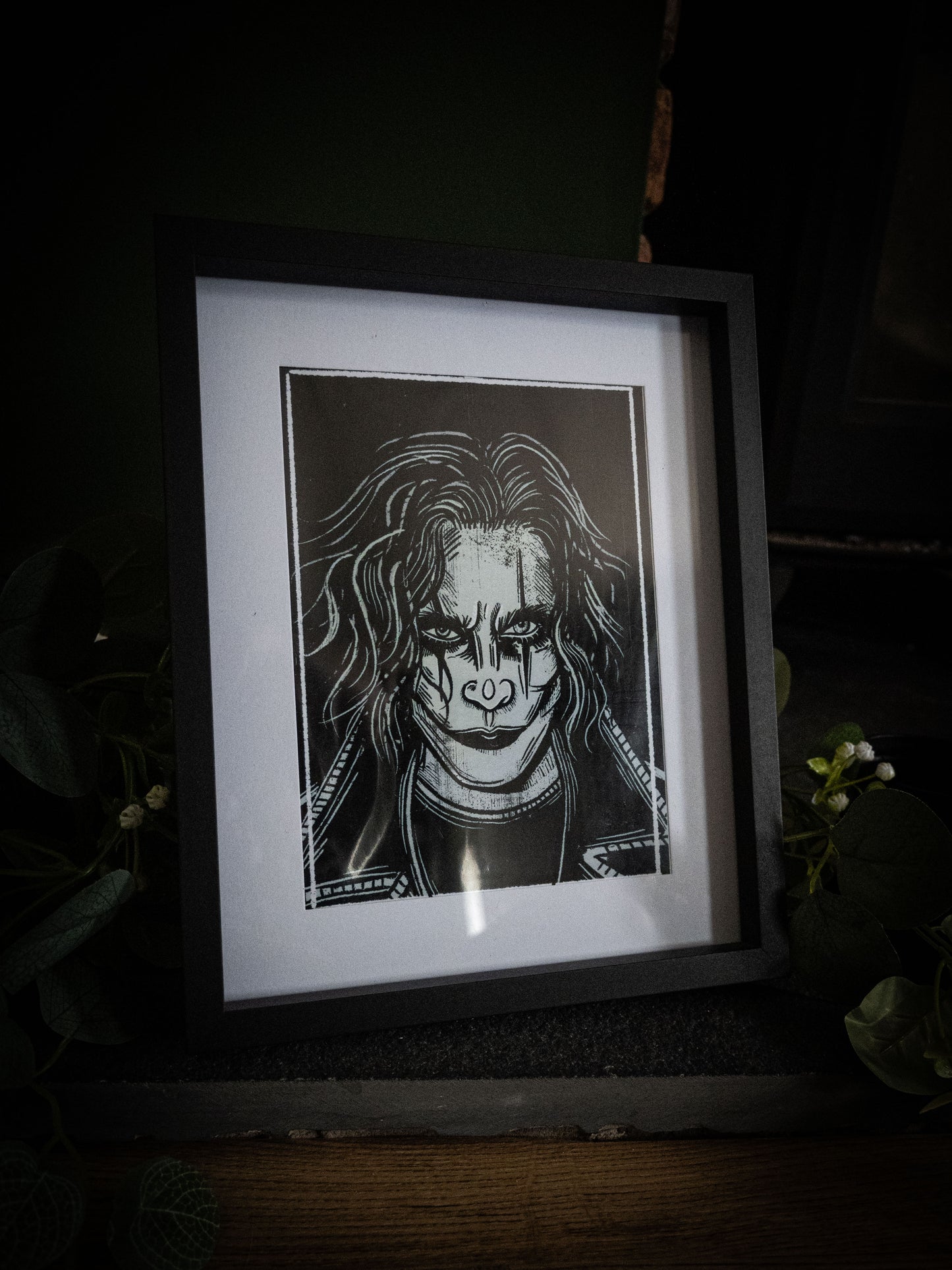 The Crow cult classic art print framed in black with green foliage