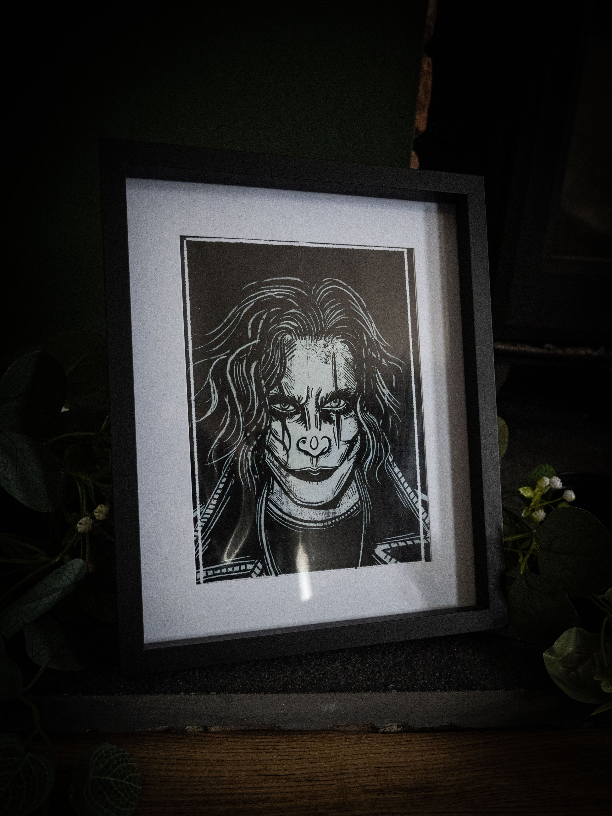 The Crow cult classic art print framed in black with green foliage