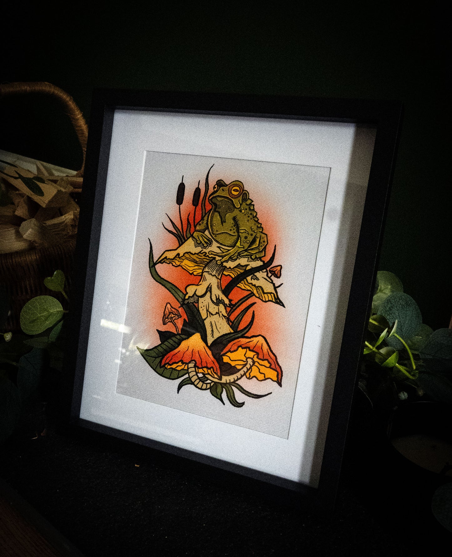 Witch's Familiar giclée print in black frame, dark moody display with foliage