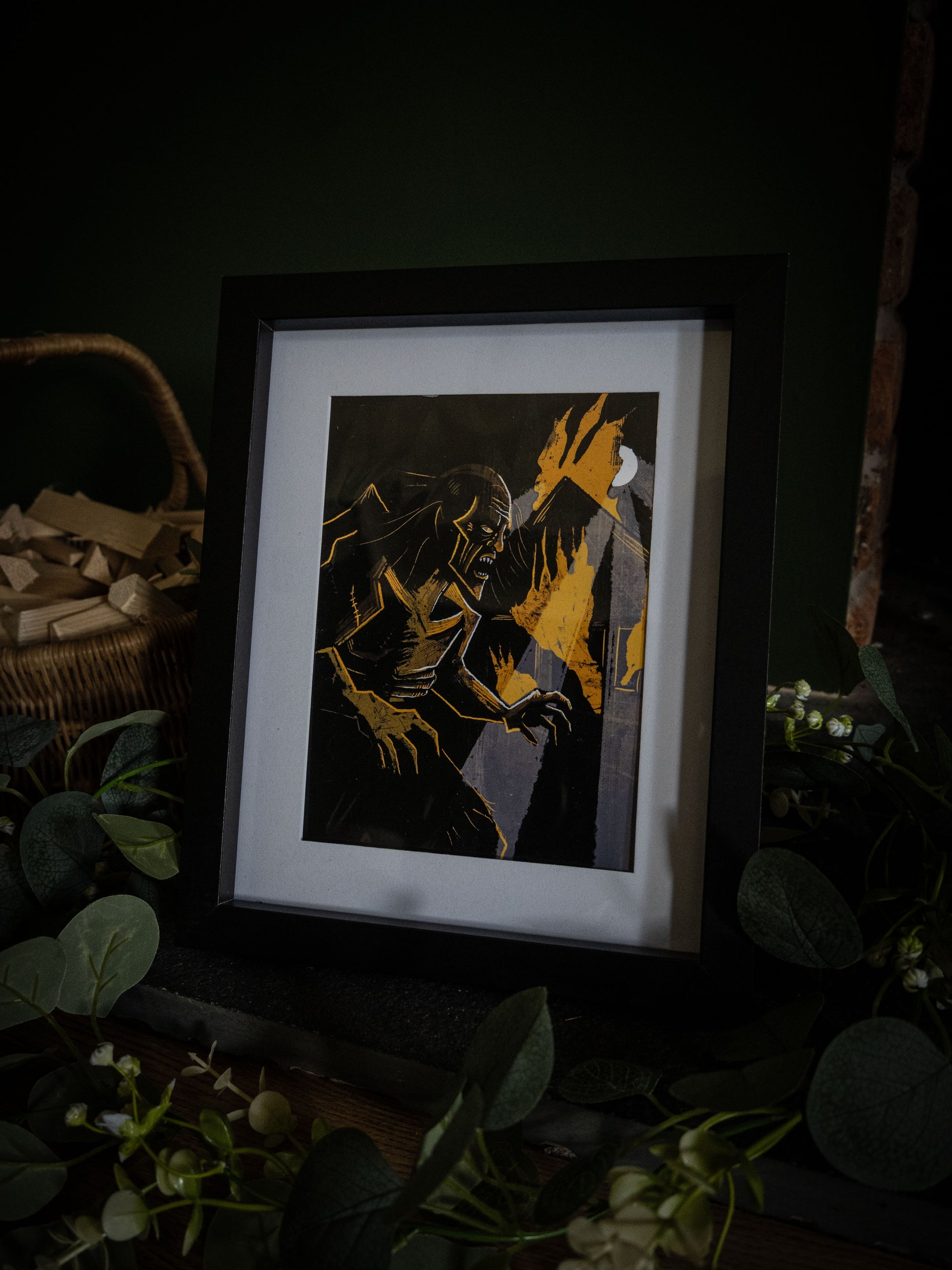 The Creature in the Flames gothic art print in black frame – angled shot showing Frankenstein's monster in amber flames, dark moody product photography