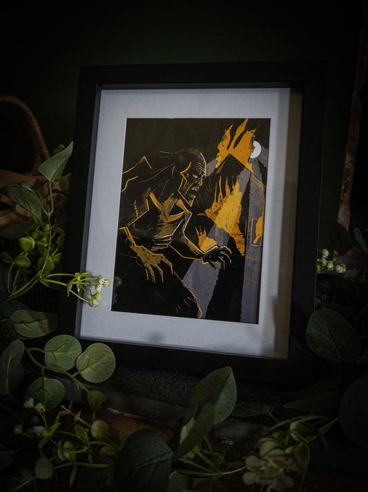Framed Frankenstein creature print – gaunt monster with clawed hands against gold fire and moonlight, botanical dark styling with white flowers and eucalyptus