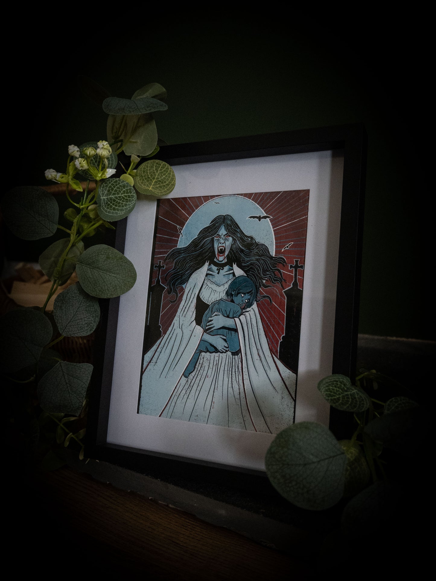 Lucy Westenra horror art print framed in black surrounded by green leaves