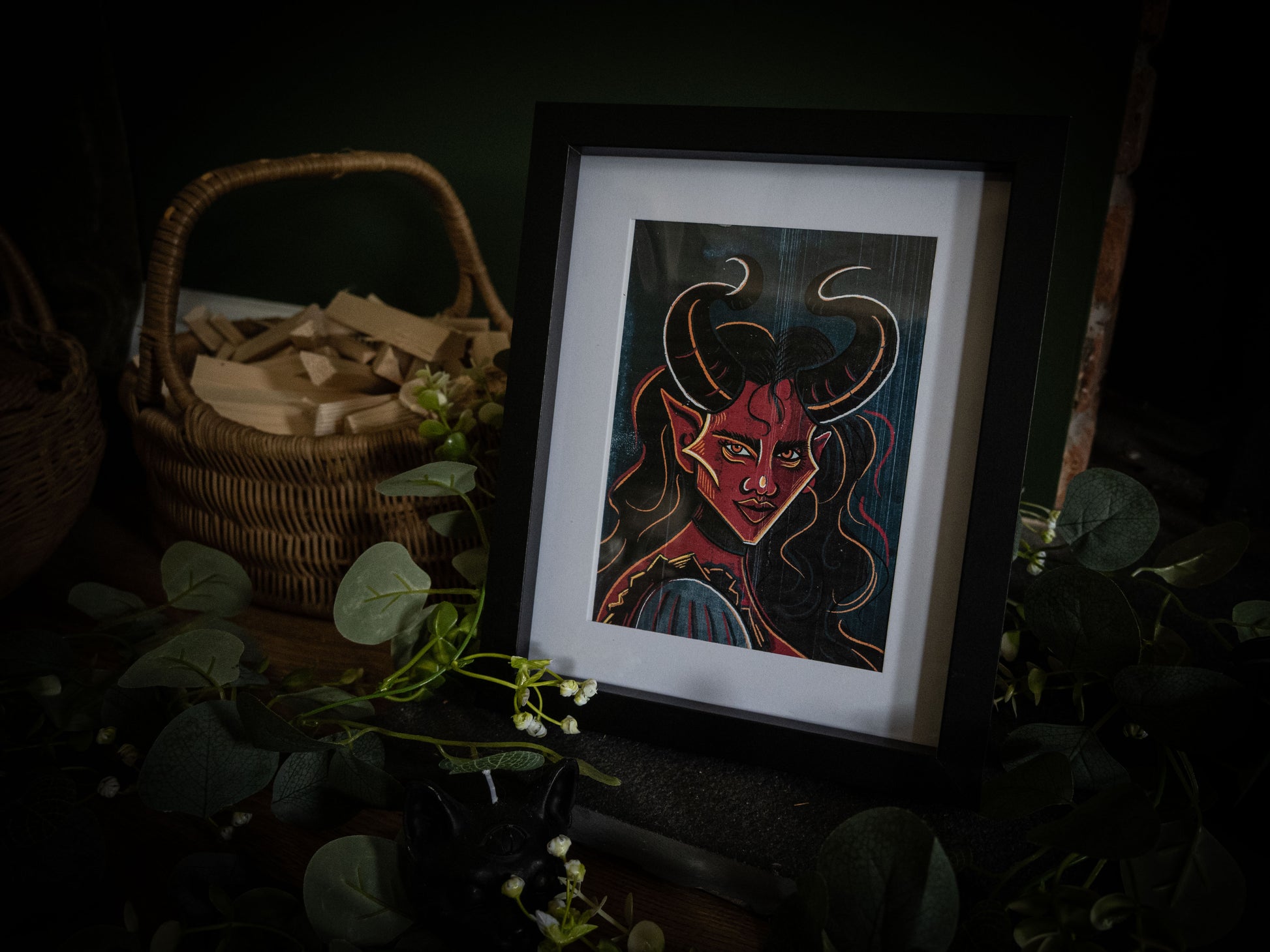 Sophie Atkinson Illustration – The Horned Temptress gothic demon print in black frame with botanical dark styling and wicker basket