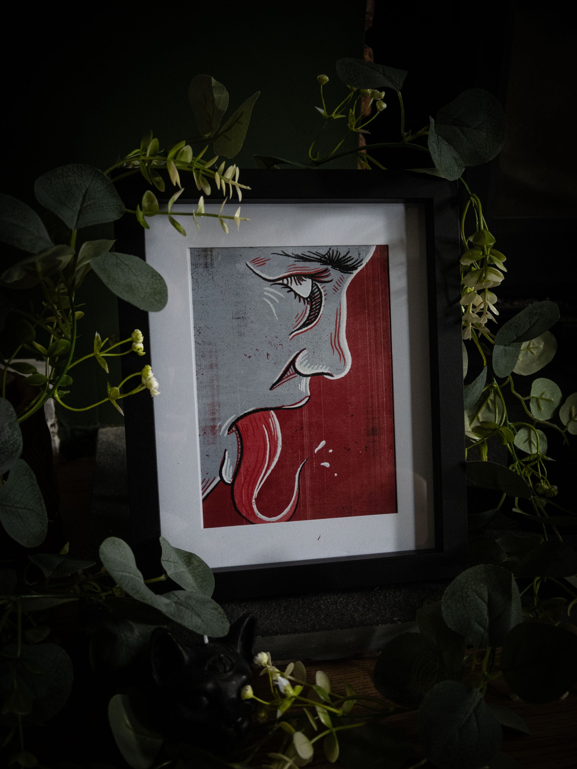 Framed Speak No Evil linocut print – gothic face profile in red and silver, styled with trailing eucalyptus