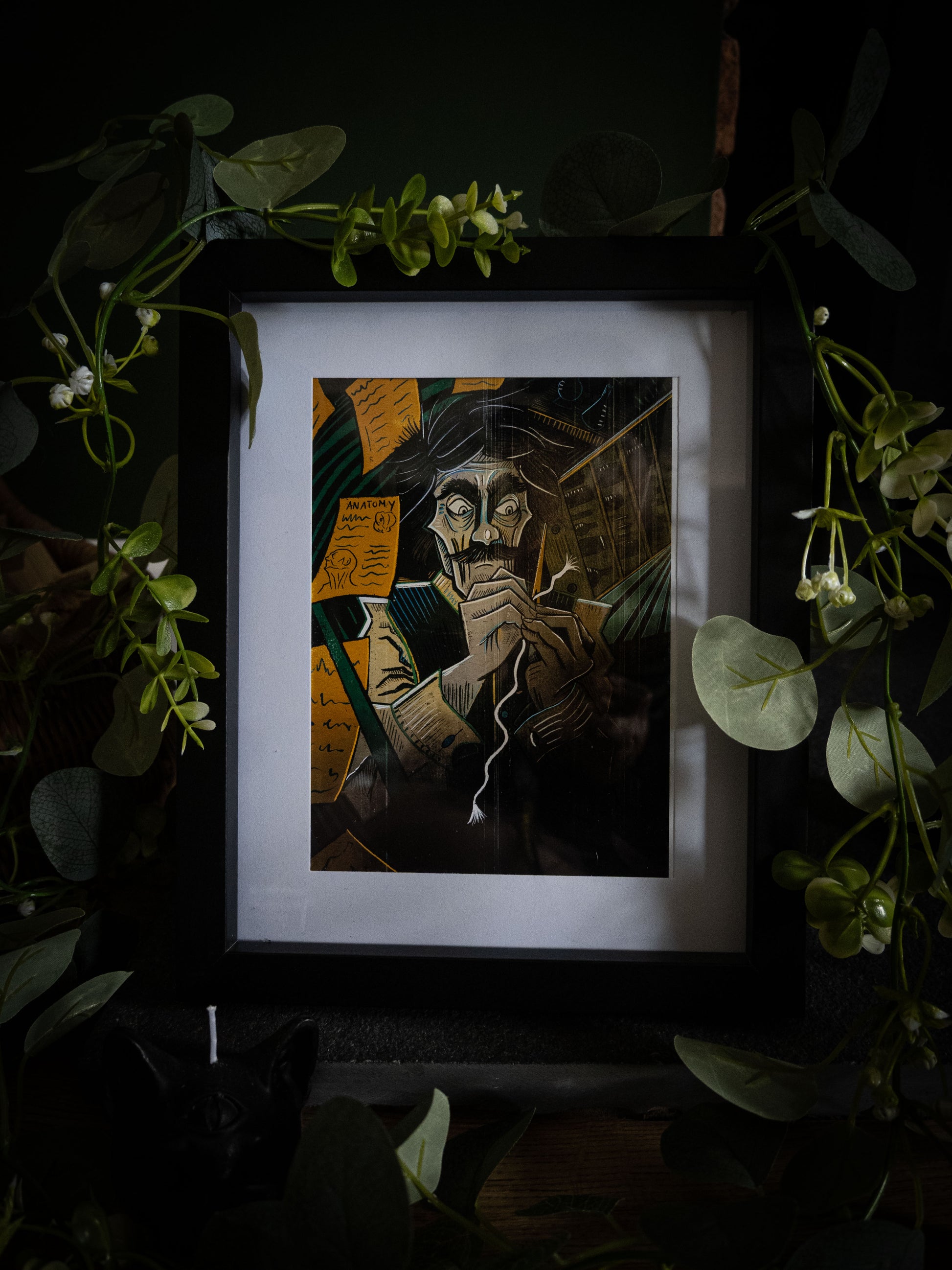 Victor art print in black frame with trailing foliage — Victor Frankenstein hunched over his creation, amber and teal colour illustration by Sophie Atkinson